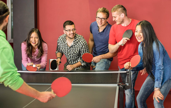 group-of-happy-young-friends-playing-ping-pong-table-tennis-shutterstock_270733406-2-585x369