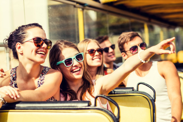 group-of-smiling-friends-traveling-by-tour-bus-shutterstock_281448020-2-585x390