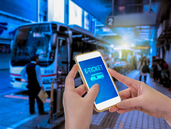 hand-holding-mobile-phone-with-e-ticket-word-with-blur-bus-terminal-background-shutterstock_360686624-2-585x439