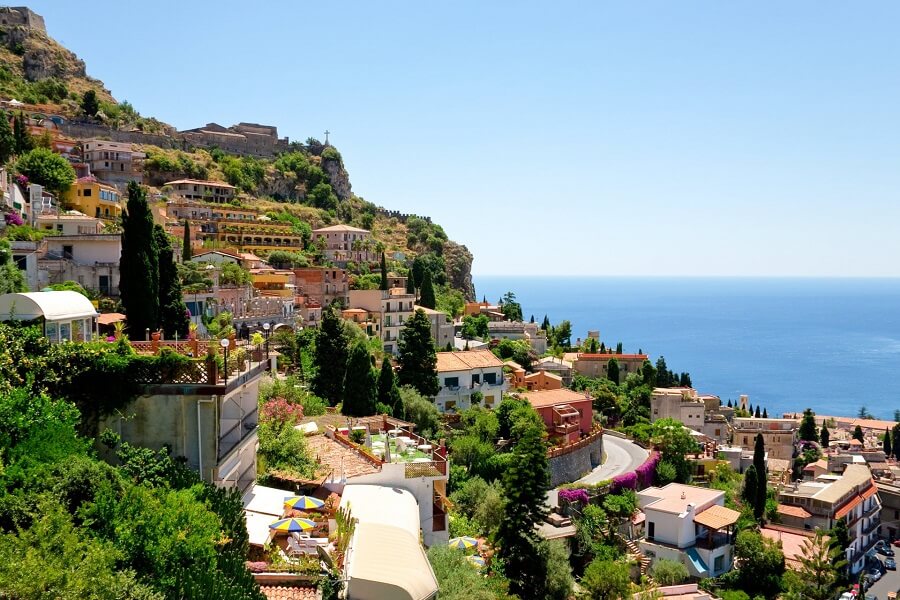 Kleine Häuser schmiegen sich an einen Berghang auf Sizilien
