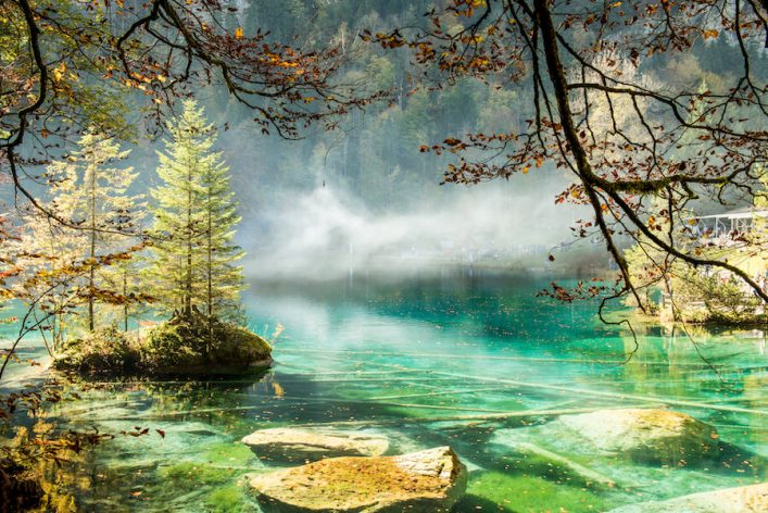 Scenery-autumn-view-on-mountain-Blue-Lake-Blausee-in-sunny-day-with-turquoise-water-and-golden-leaves_shutterstock_1015524514_900