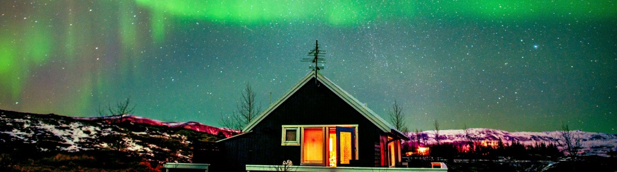 northern-lights-visible-above-small-cabin-in-iceland-istock_000066132119_large