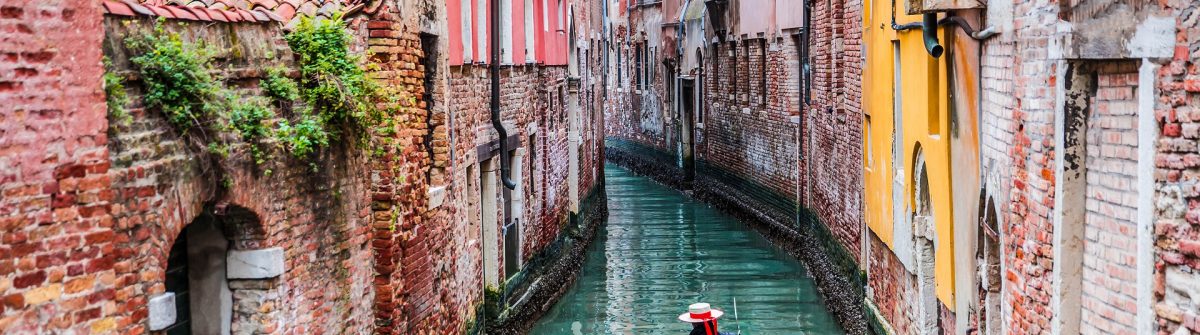 venetian-gondolier-punting-gondola-through-green-canal-waters-of-venice-italy-shutterstock_267588308-2
