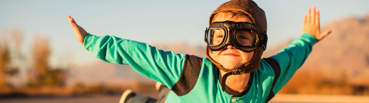 Young Boy with Goggles Imagines Flying on Suitcase