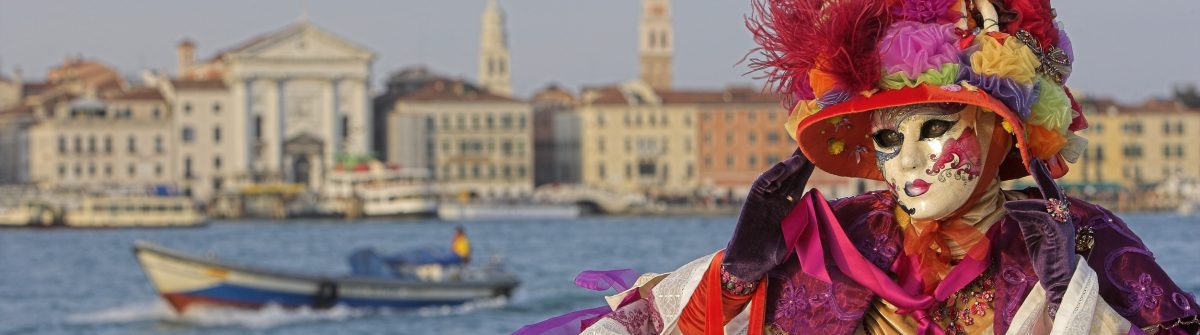 Female mask with colorful costume at Grand Canal in Venice