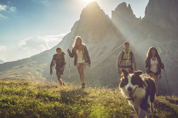 Personengruppe wandert mit ihrem Hund in den Bergen.