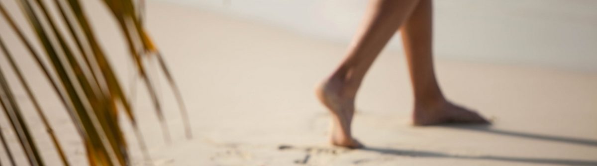 unrecognizable woman walking away from her bikini left in sand