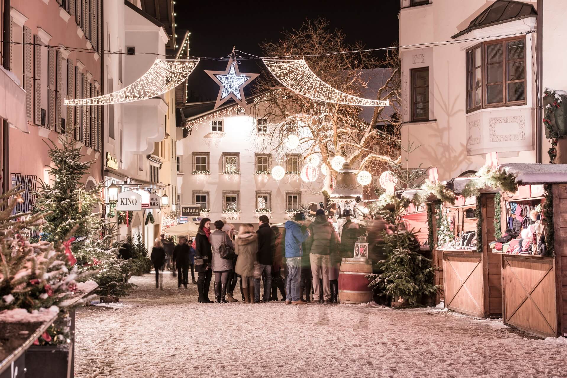 Menschen trinken im Winter Glühwein auf dem Weihnachtsmarkt in Kitzbühel in Tirol. 