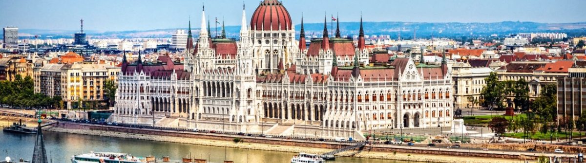 Das markante ungarische Parlamentsgebäude mit seiner imposanten, roten Kuppel steht am Ufer der Donau in Budapest. Perfekt für Bootstouren, Spaziergänge entlang des Ufers und einen Besuch der Fischerbastei.