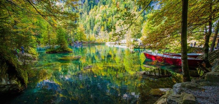 yellow-leaves-and-red-boat-at-blausee-blue-lake-nature-park-kandersteg-switzerland-shutterstock_127214768-2-707×338-1