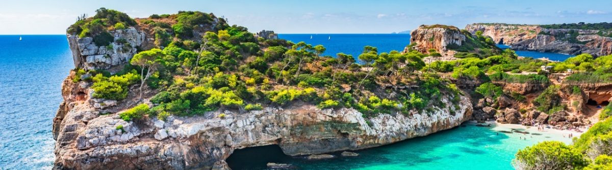 Türkisblaues Wasser umspült Caló des Moro, einen der Top 20 schönsten Orte Mallorcas, mit steilen Felswänden und grüner Vegetation.